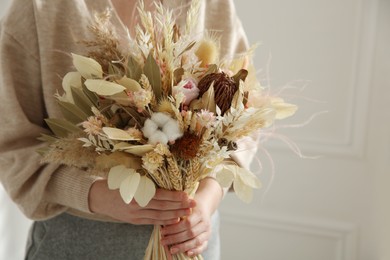 Photo of Woman holding beautiful dried flower bouquet at home, closeup