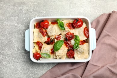 Photo of Tasty ravioli with tomato sauce served on grey table, top view