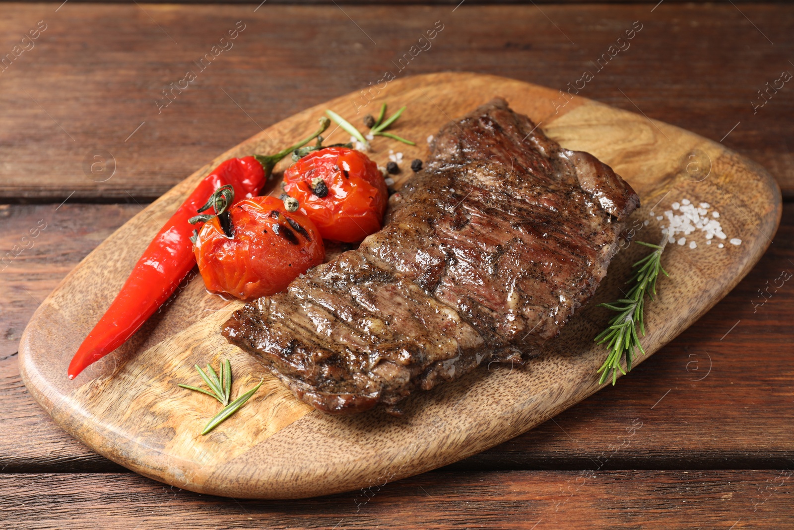 Photo of Delicious roasted beef meat, vegetables and spices on wooden table