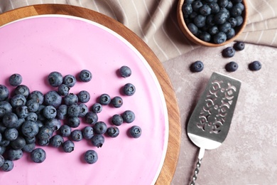 Wooden stand with tasty blueberry cake on grey table, flat lay