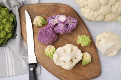 Photo of Various cauliflower cabbages on light grey table, flat lay