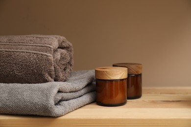 Photo of Soft towels and candles on wooden shelf indoors, closeup