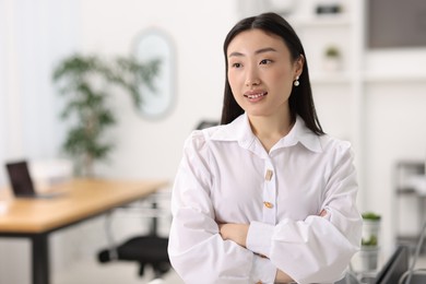 Photo of Portrait of smiling businesswoman with crossed arms in office. Space for text