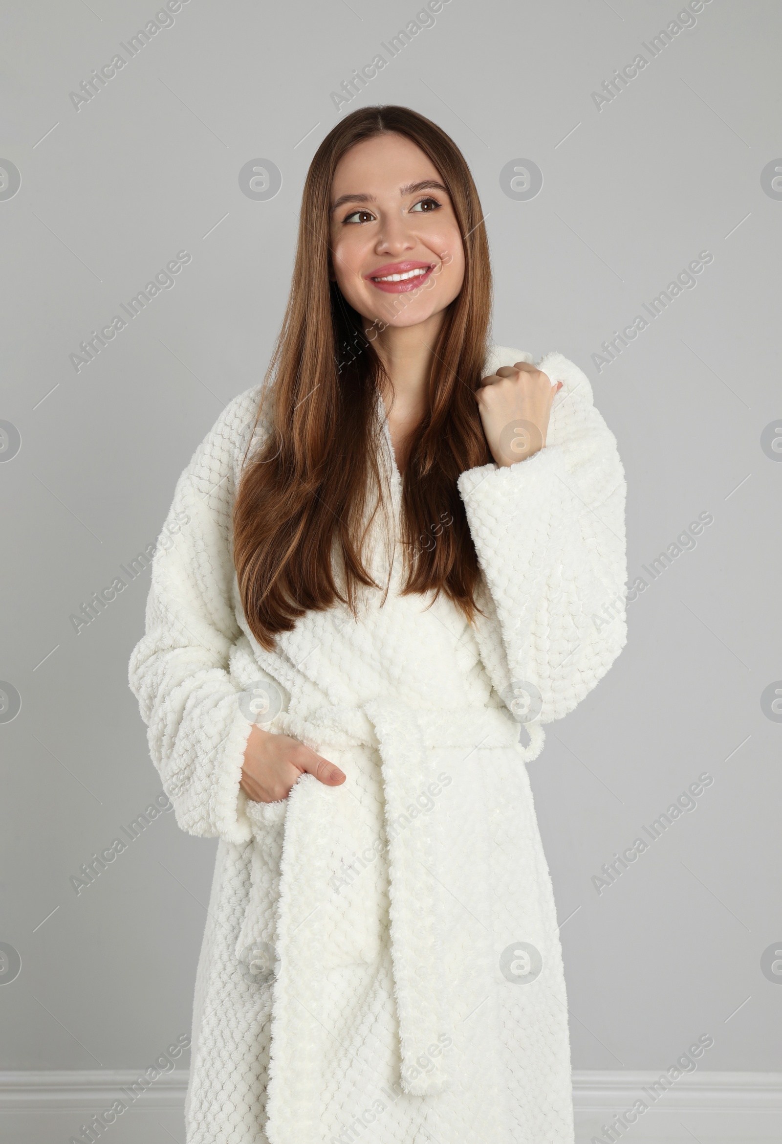 Photo of Beautiful young woman in bathrobe on light grey background