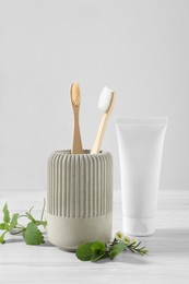 Photo of Toothbrushes, toothpaste and herbs on white wooden table