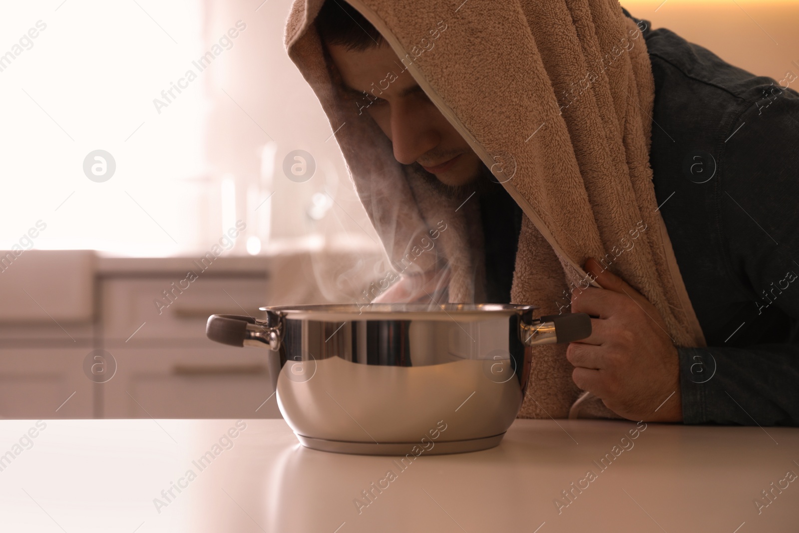 Photo of Man taking treatments at table indoors. Steam inhalation