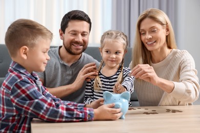Photo of Planning budget together. Family with piggy bank and coins at table indoors