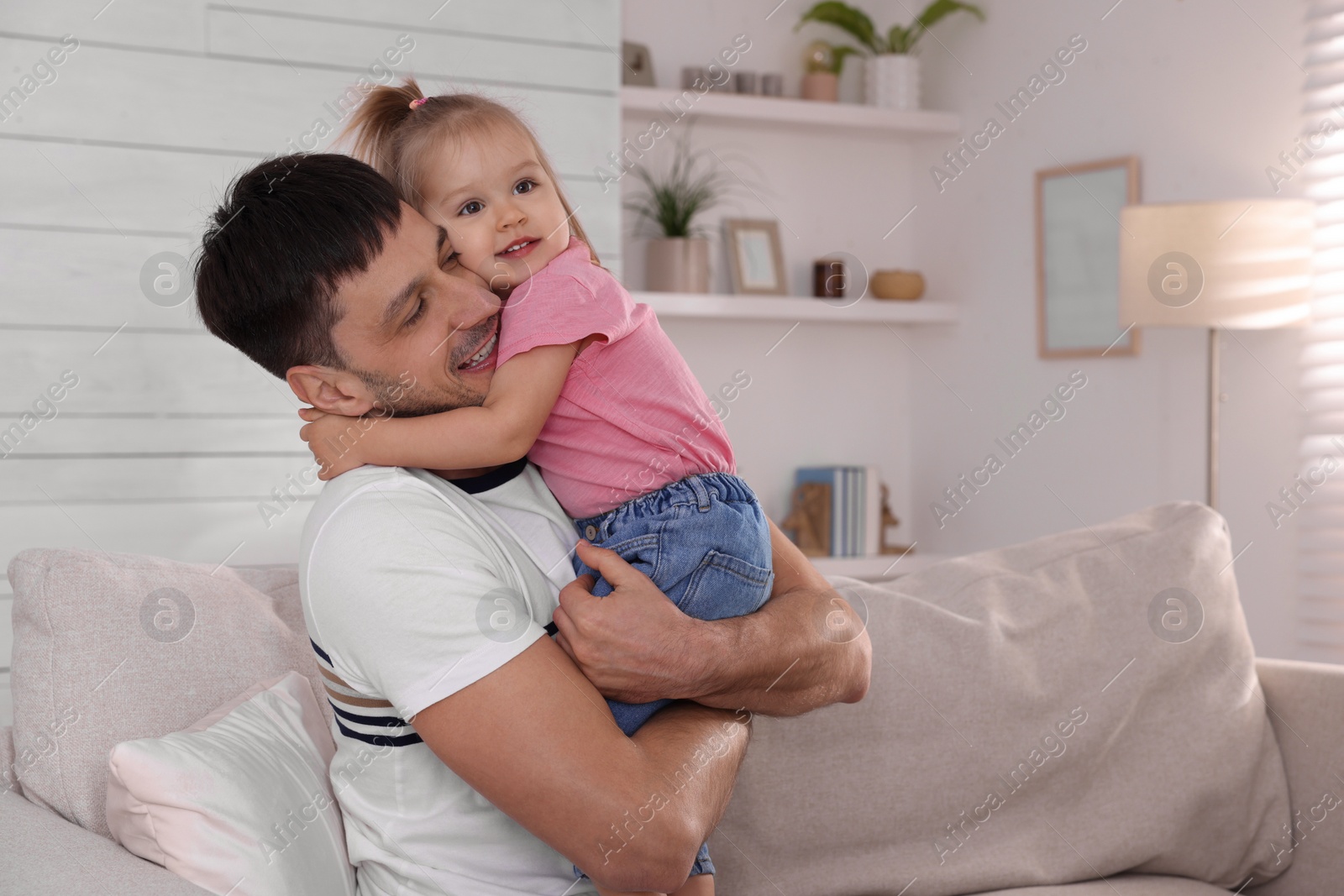 Photo of Father with his cute little daughter on sofa at home