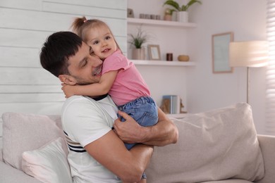 Photo of Father with his cute little daughter on sofa at home