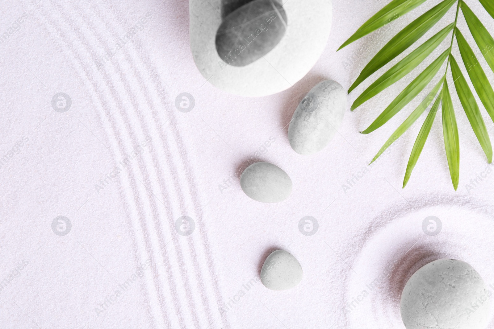 Photo of Zen garden stones and green leaves on white sand with pattern, flat lay. Space for text