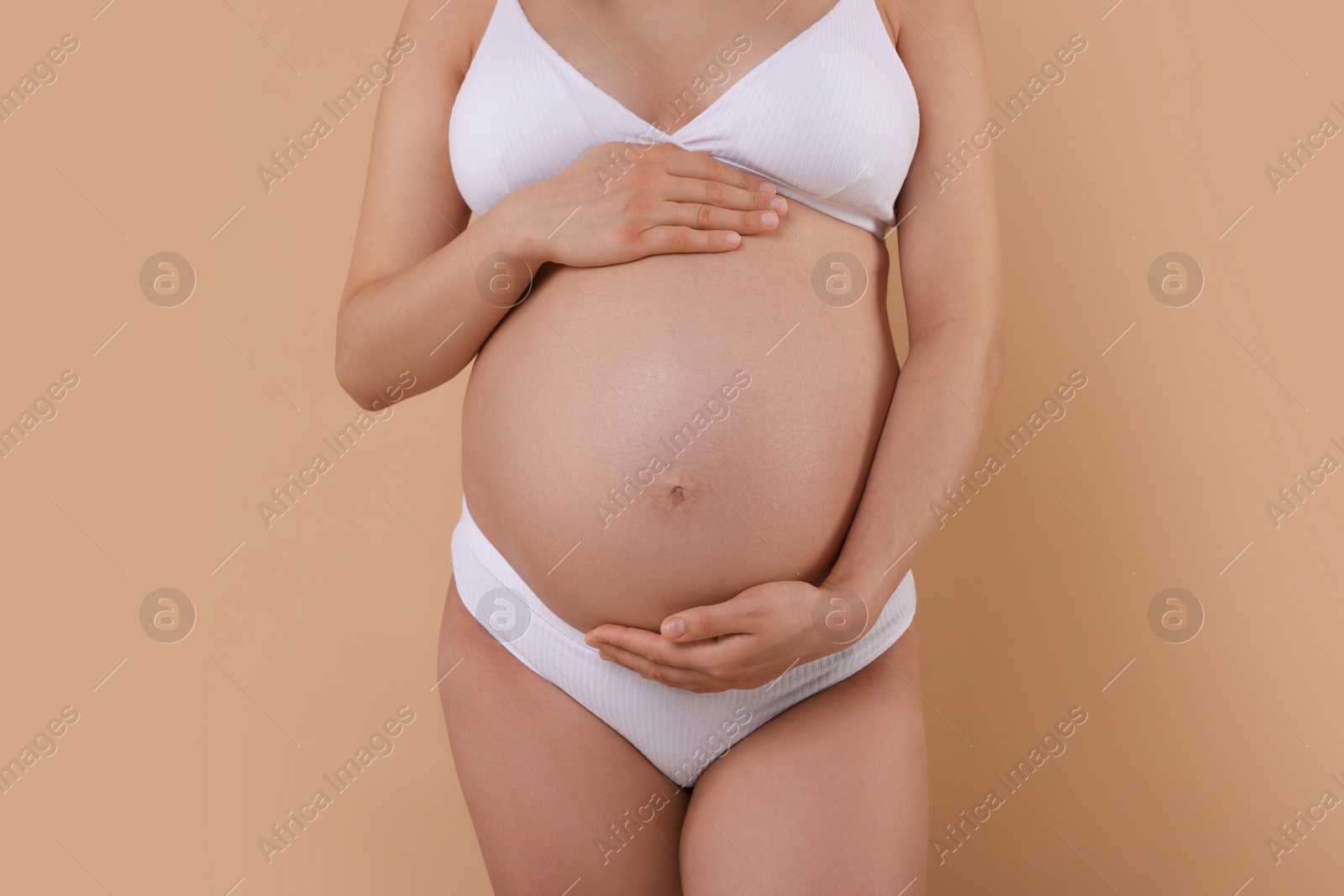 Photo of Pregnant woman in stylish comfortable underwear on beige background, closeup