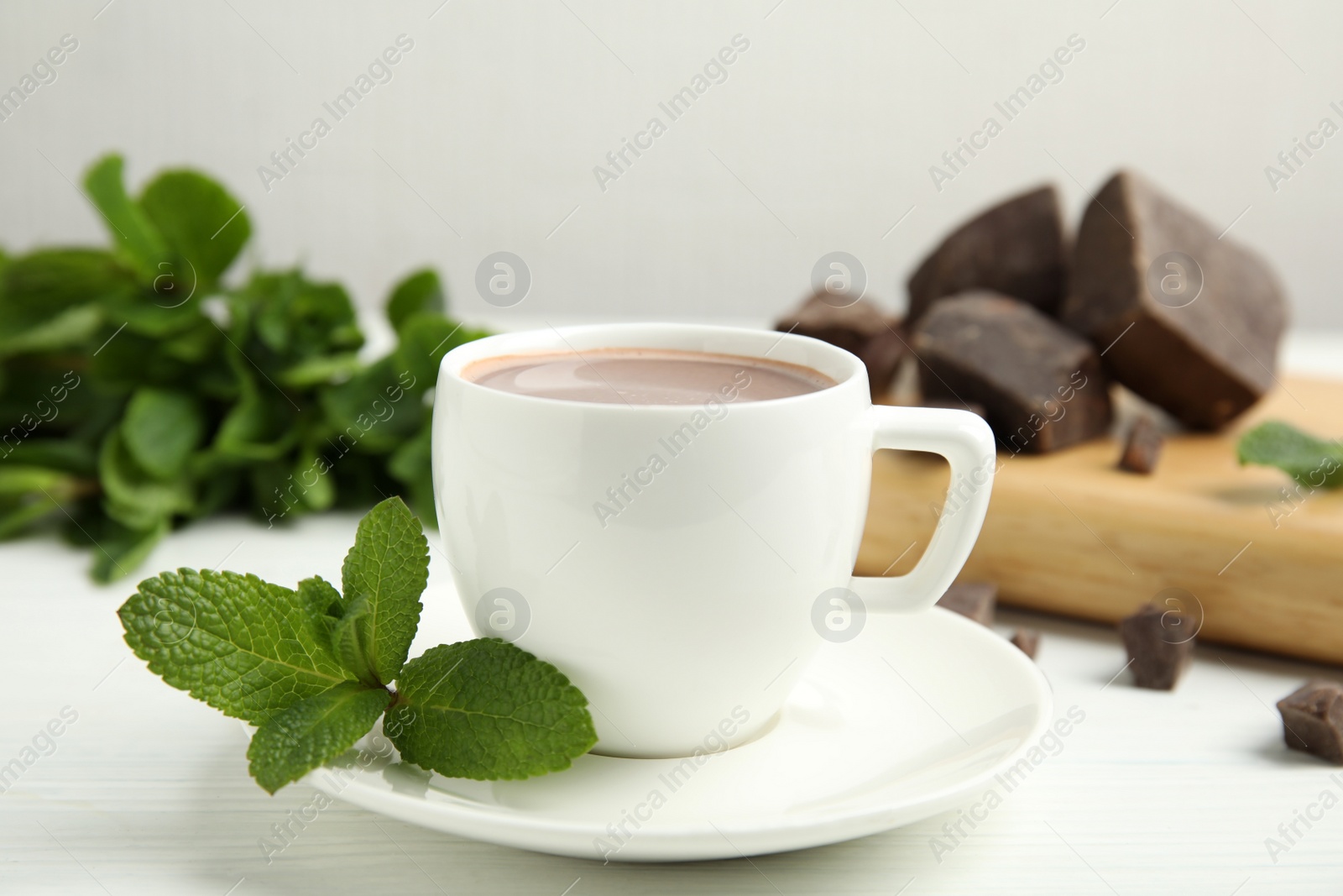 Photo of Cup of delicious hot chocolate and fresh mint on white wooden table