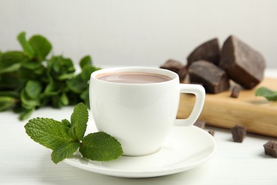 Cup of delicious hot chocolate and fresh mint on white wooden table