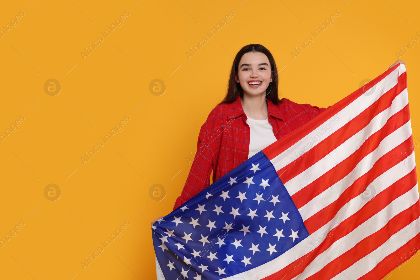 Photo of 4th of July - Independence Day of USA. Happy girl with American flag on yellow background, space for text