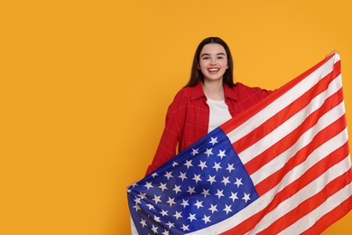 Photo of 4th of July - Independence Day of USA. Happy girl with American flag on yellow background, space for text