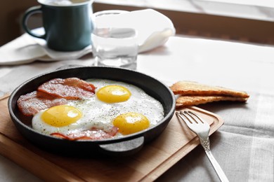 Photo of Tasty fried eggs with bacon and toasts on table, space for text
