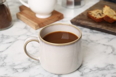 Cup of fresh aromatic coffee on white marble table