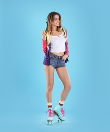 Young woman with retro roller skates on color background