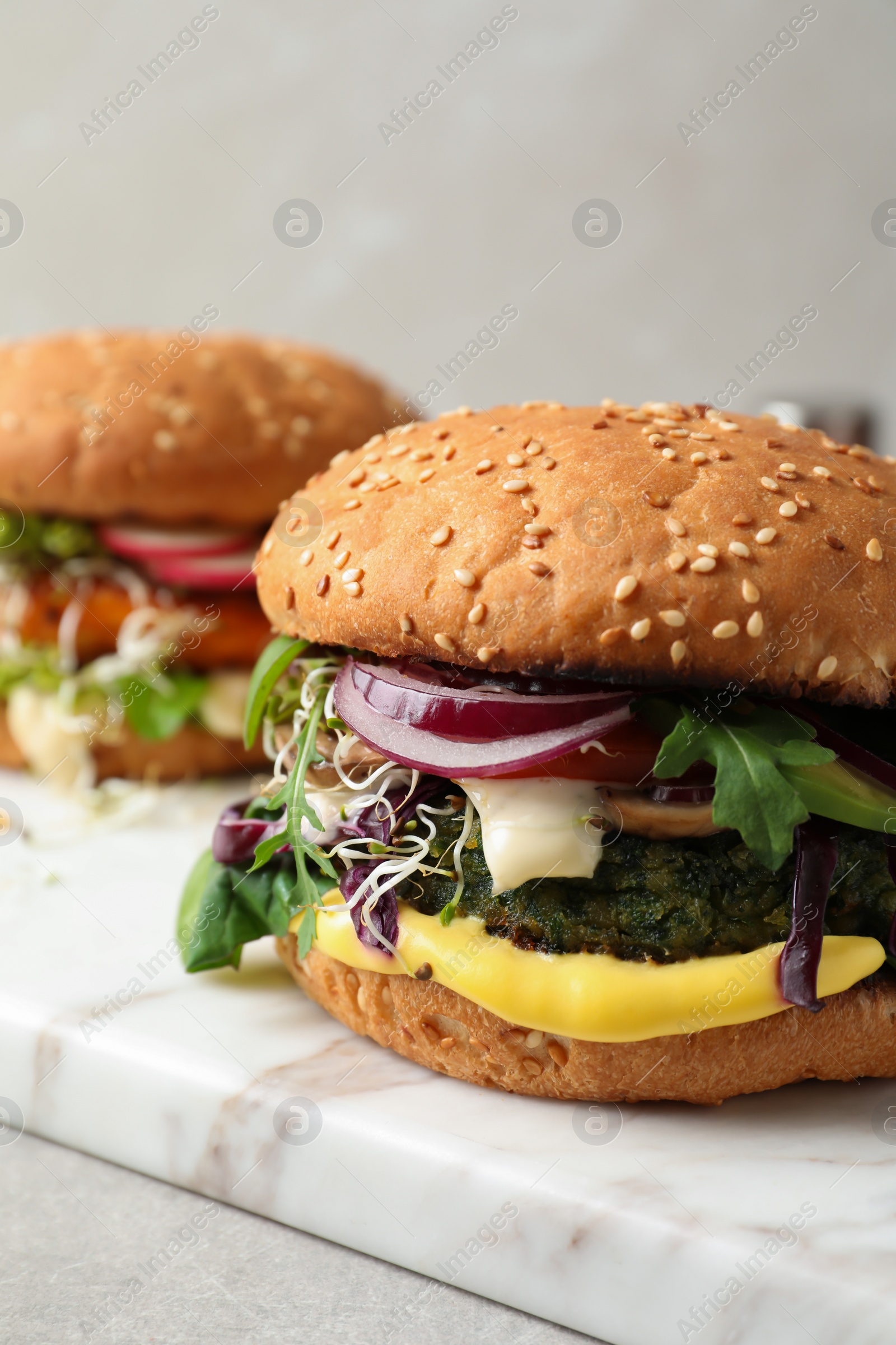 Photo of Tasty vegetarian burgers on marble board
