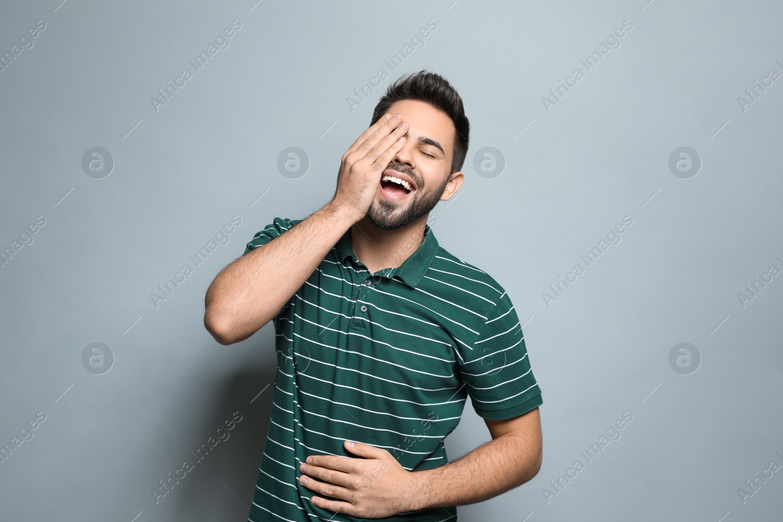 Photo of Young man laughing on light grey background. Funny joke