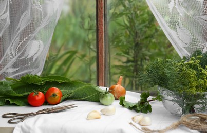 Photo of Fresh green herbs, tomatoes, garlic cloves and onion on table indoors