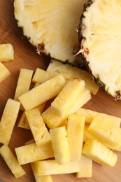 Photo of Pieces of tasty ripe pineapple on wooden table, flat lay