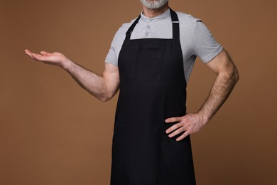 Photo of Man wearing kitchen apron on brown background, closeup. Mockup for design