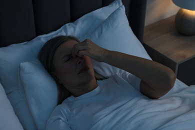 Woman suffering from headache in bed at night