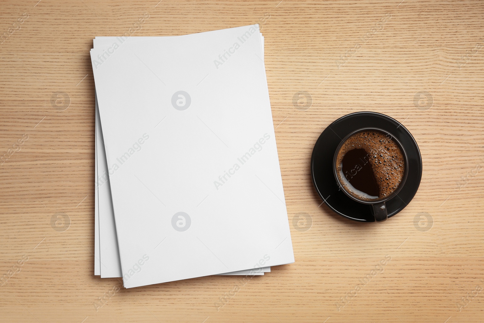 Photo of Blank paper sheets for brochure and cup of coffee on wooden background, flat lay. Mock up