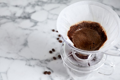 Photo of Brewing tasty coffee using drip filter on white marble table, closeup. Space for text