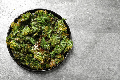 Tasty baked kale chips on grey table, top view