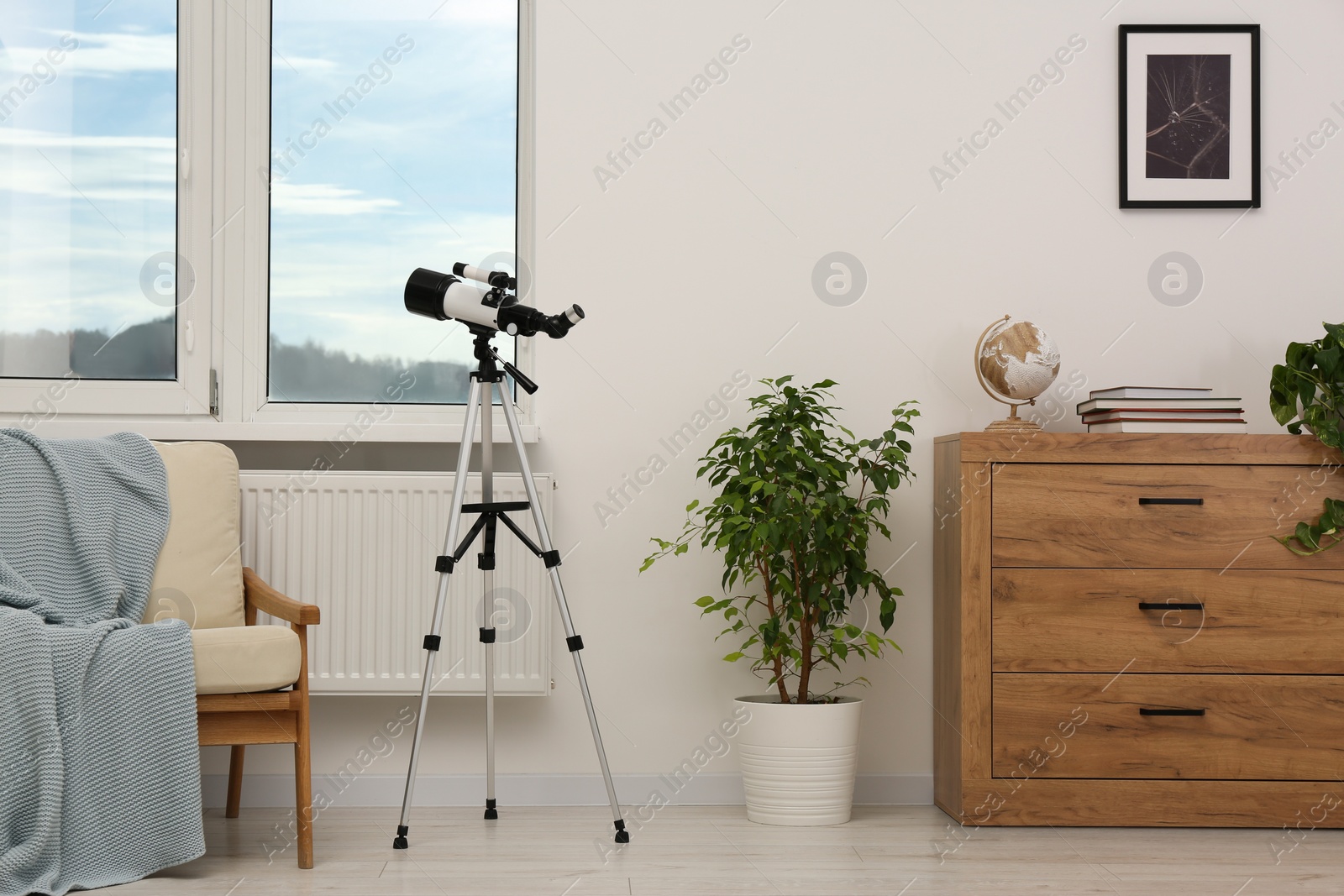 Photo of Tripod with modern telescope in stylish room