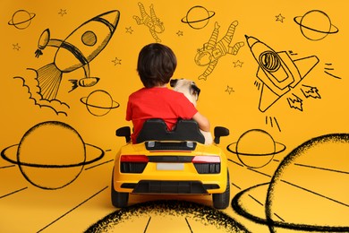 Cute little boy with his dog in toy car and drawing of space on yellow background