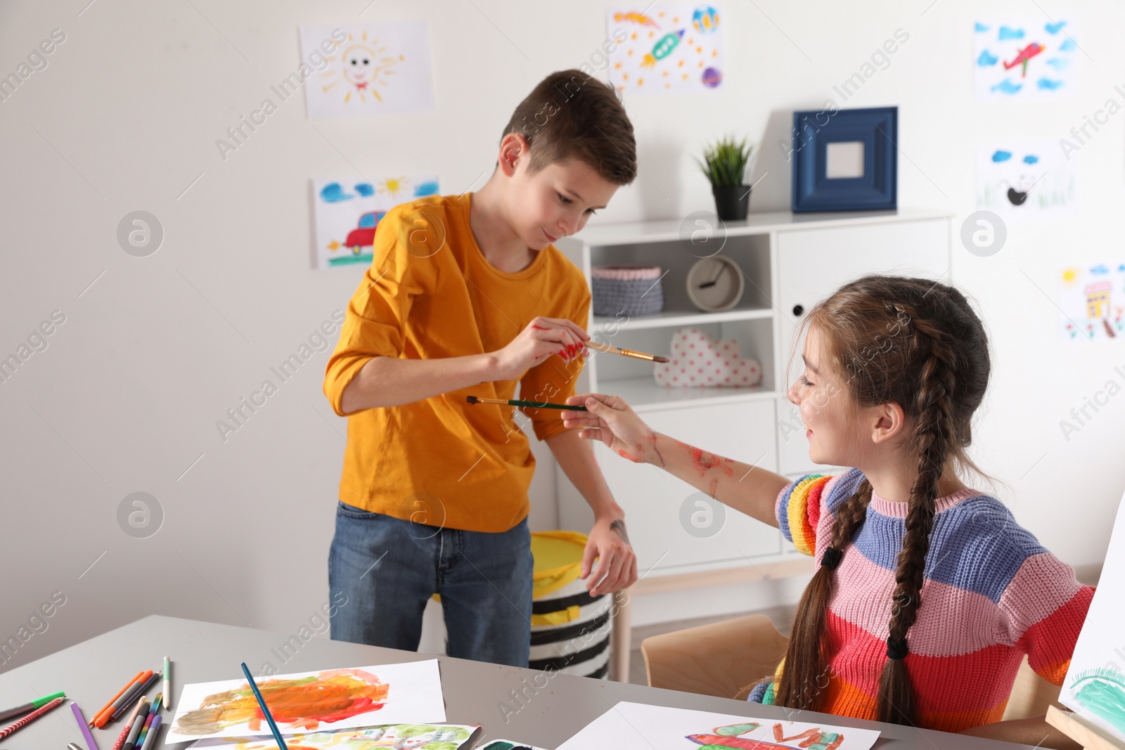 Photo of Little children having fun with paints at table indoors