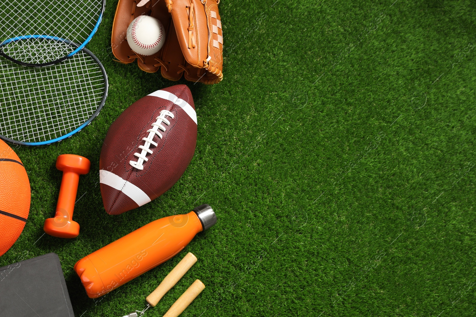 Photo of Different sports equipment on green grass, flat lay. Space for text