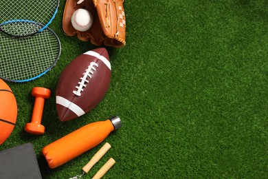 Photo of Different sports equipment on green grass, flat lay. Space for text