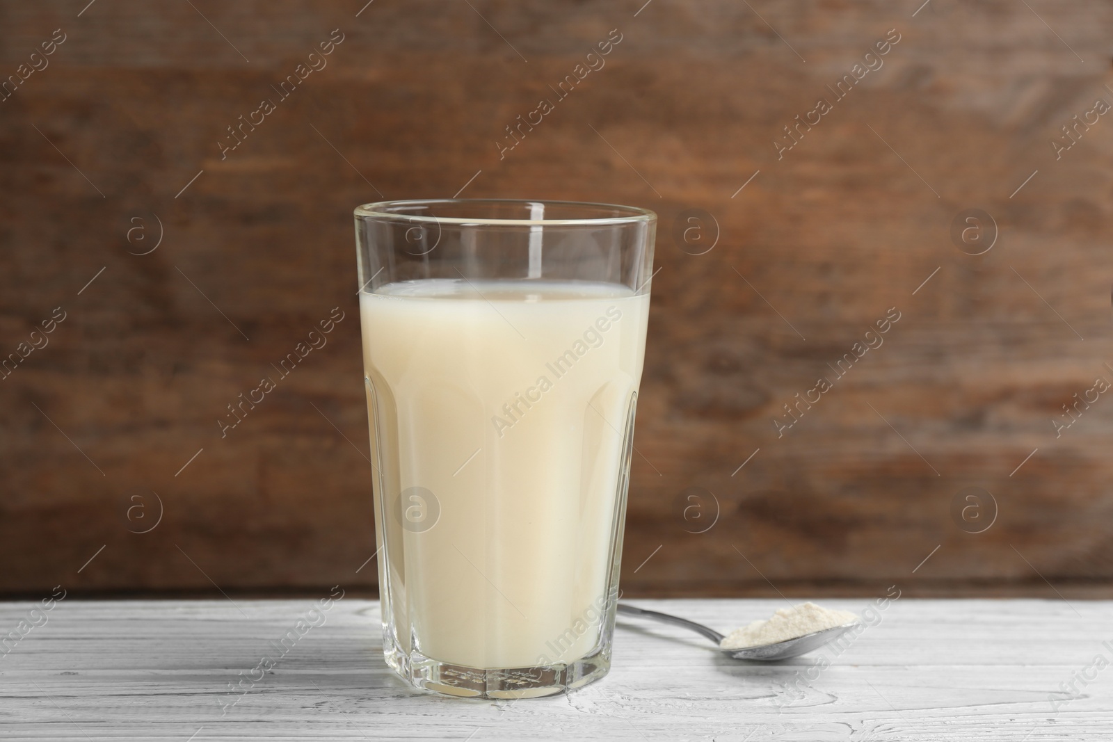 Photo of Protein shake and powder on white wooden table