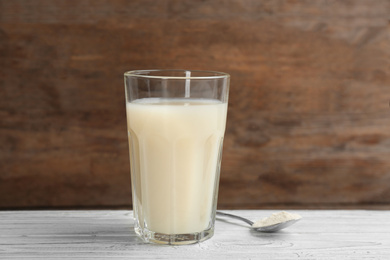 Photo of Protein shake and powder on white wooden table