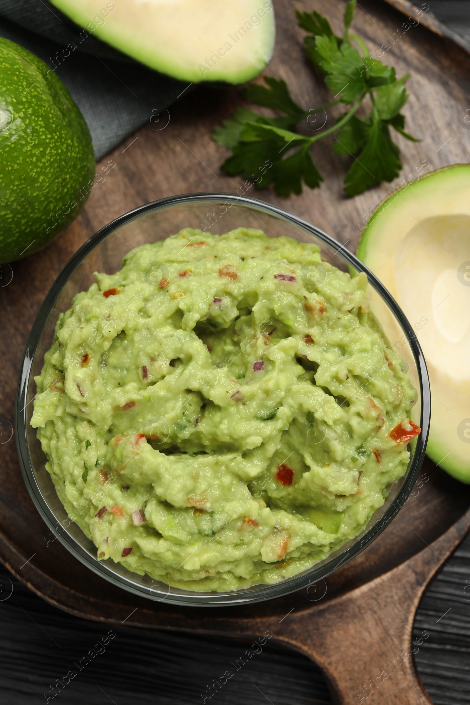 Photo of Delicious guacamole with parsley and fresh avocado on wooden table, flat lay