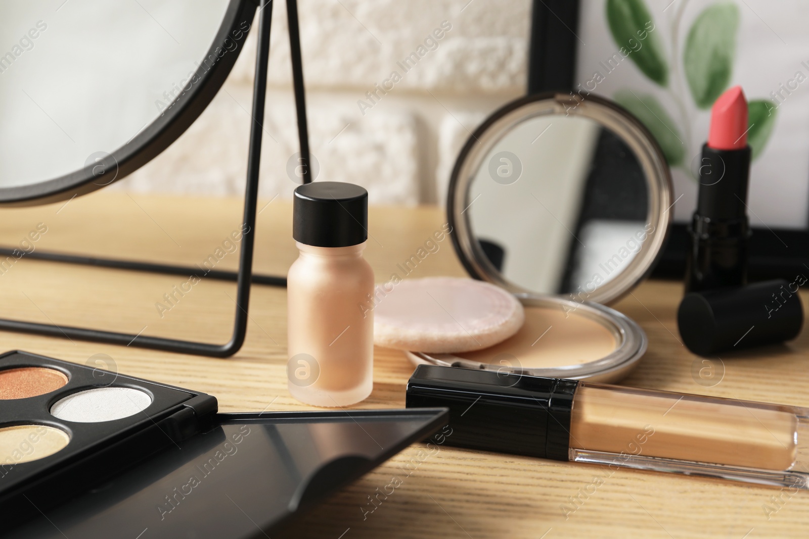 Photo of Mirror and makeup products on wooden dressing table, closeup