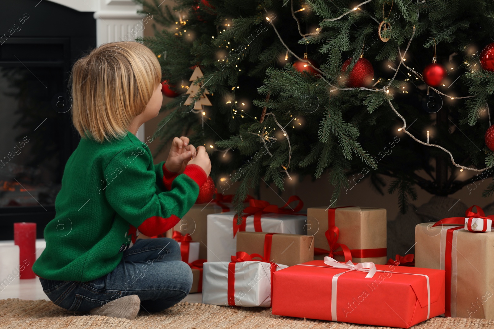 Photo of Little child decorating Christmas tree at home