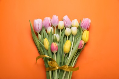 Photo of Bouquet of beautiful tulips on orange background, top view