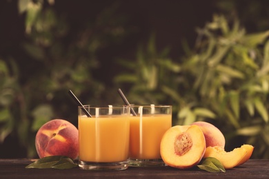 Photo of Natural peach juice and fresh fruits on wooden table