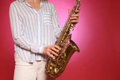 Photo of Woman with saxophone on red background, closeup. Space for text