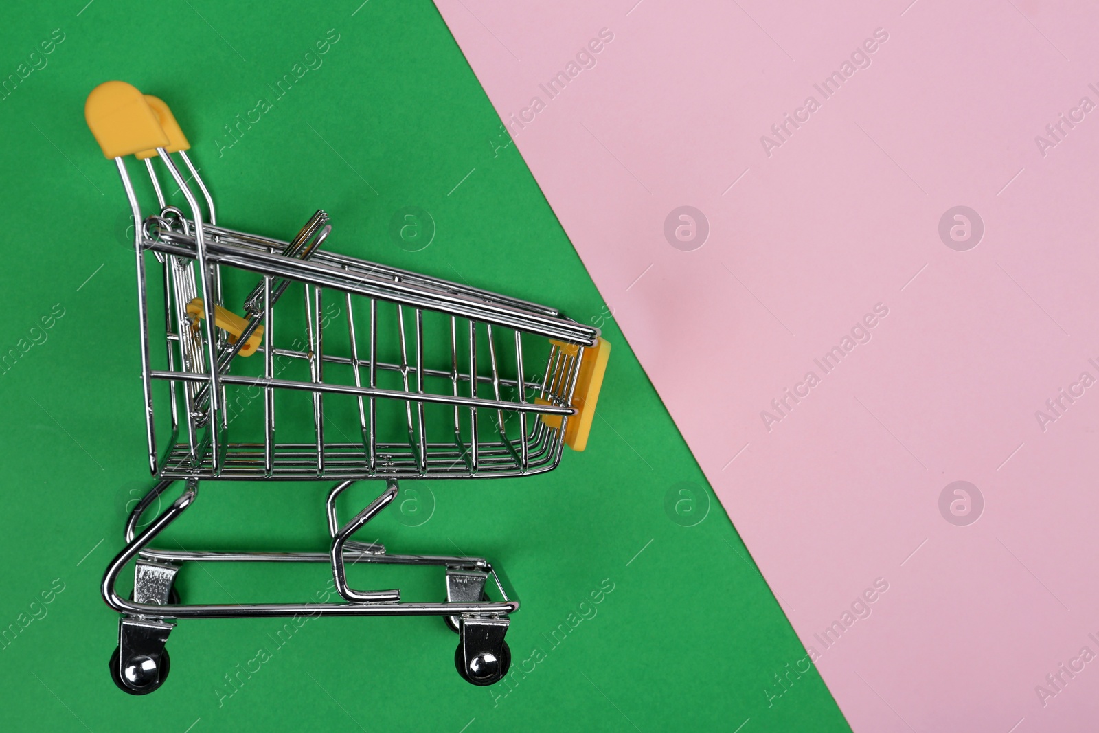 Photo of Empty shopping trolley on color background, top view. Space for text