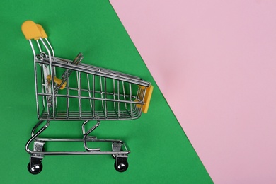 Empty shopping trolley on color background, top view. Space for text