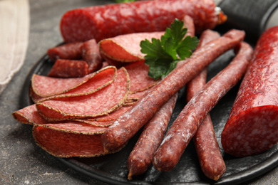 Photo of Different tasty sausages on grey table, closeup