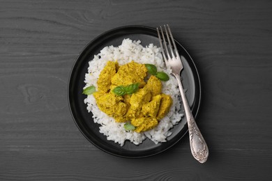 Photo of Delicious rice and chicken with curry sauce on grey wooden table, top view