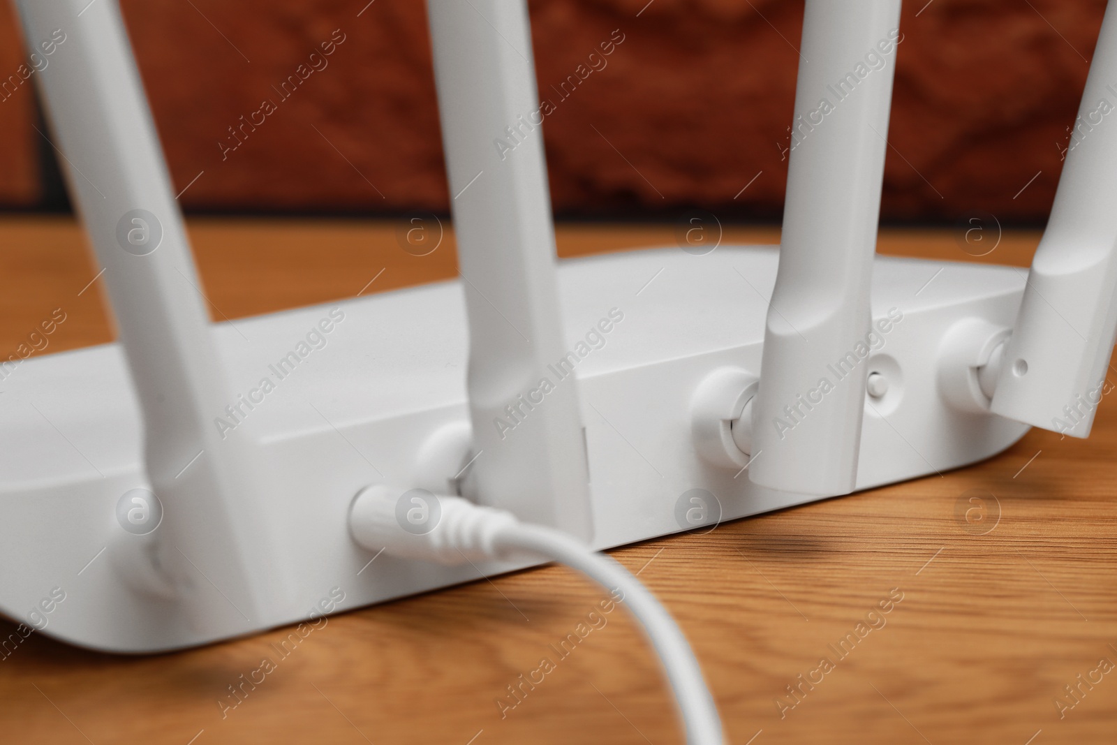 Photo of New white Wi-Fi router on wooden table, closeup