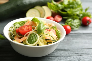 Photo of Delicious zucchini pasta with shrimps, cherry tomatoes and basil on grey wooden table